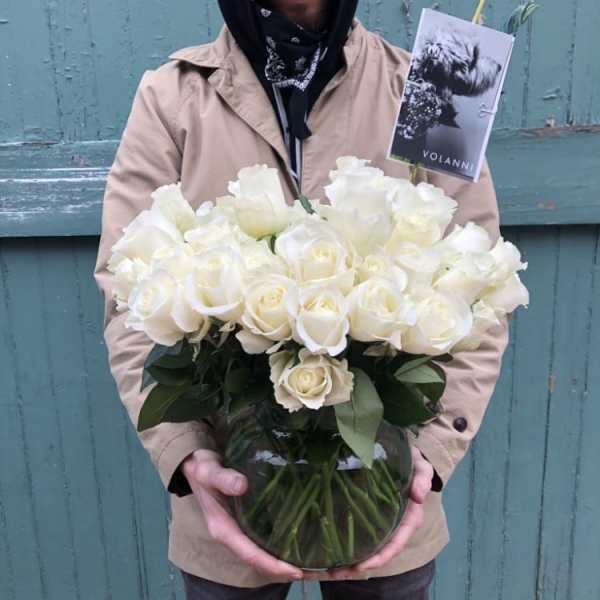 Person holding a vase of white roses