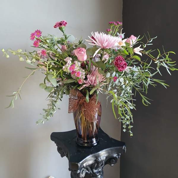 Pink mixed bouquet in a glass vase with a brown ribbon