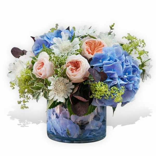 Blue and blush flowers arranged in a glass vase
