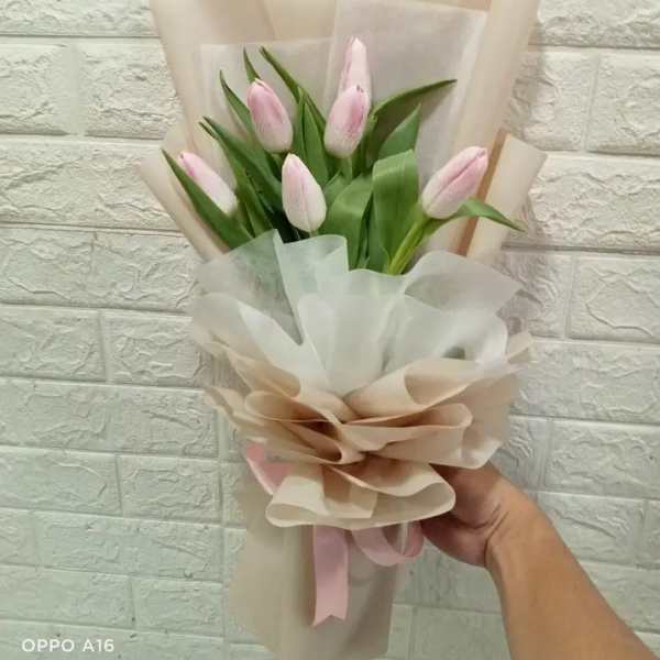 Bouquet of pale pink tulips wrapped in beige and white paper