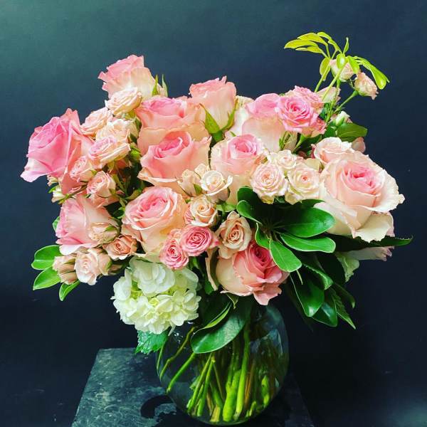 Pink roses and spray roses in a glass vase with white hydrangea