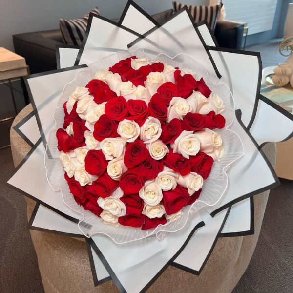 Large bouquet of red and white roses wrapped in layered white paper
