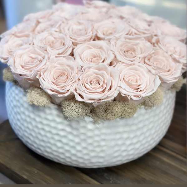 Pale pink roses arranged in a white textured bowl