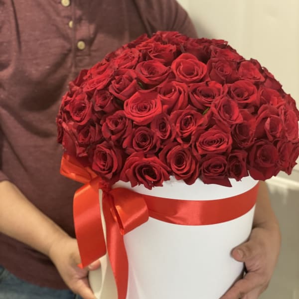 Large bouquet of red roses in a white hat box with a red ribbon
