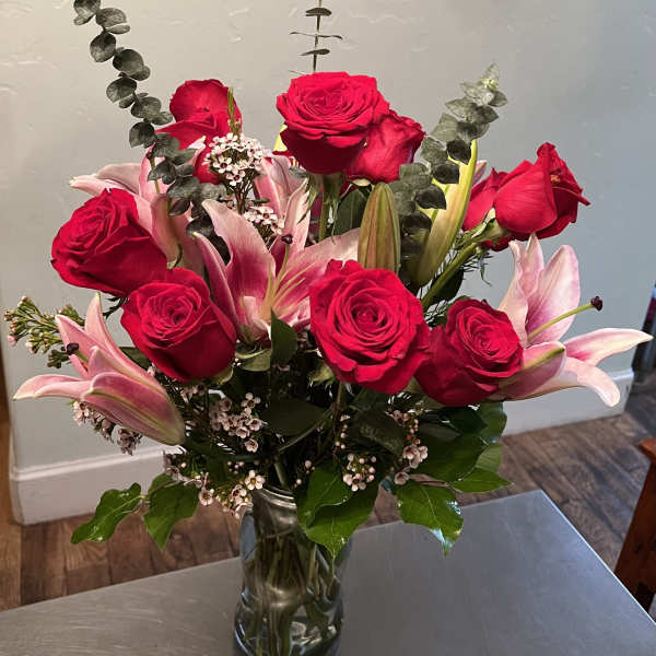 Red roses and pink lilies arranged in a clear glass vase.