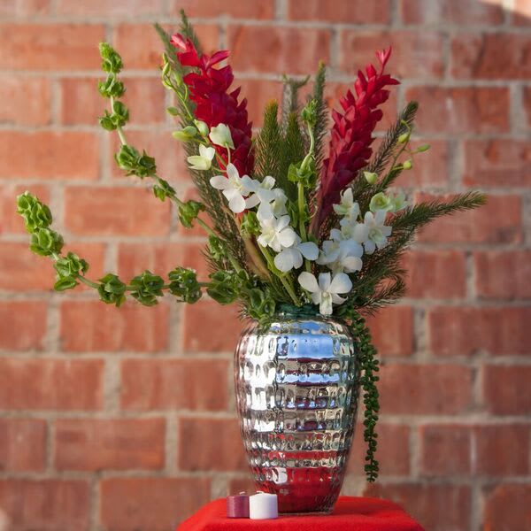 Red and white flowers arranged in a silver vase