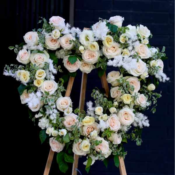 Heart-shaped floral wreath of pale roses on a wooden easel