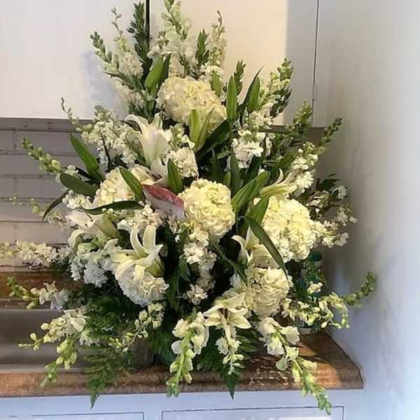 Large white floral arrangement with lilies and hydrangeas