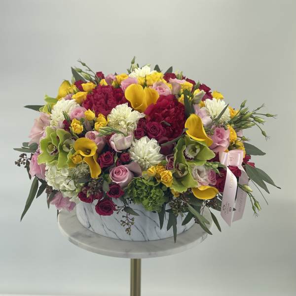 Large mixed bouquet in a marble-patterned box with pink, yellow, white, and green flowers