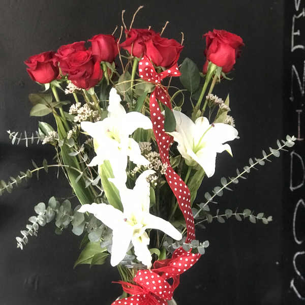 Red roses and white lilies in a glass vase with a red polka-dot ribbon