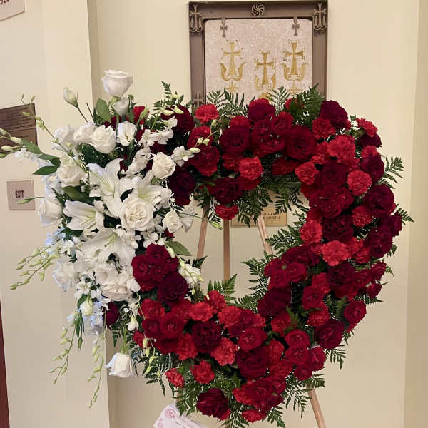 Heart-shaped floral wreath of red and white roses on an easel