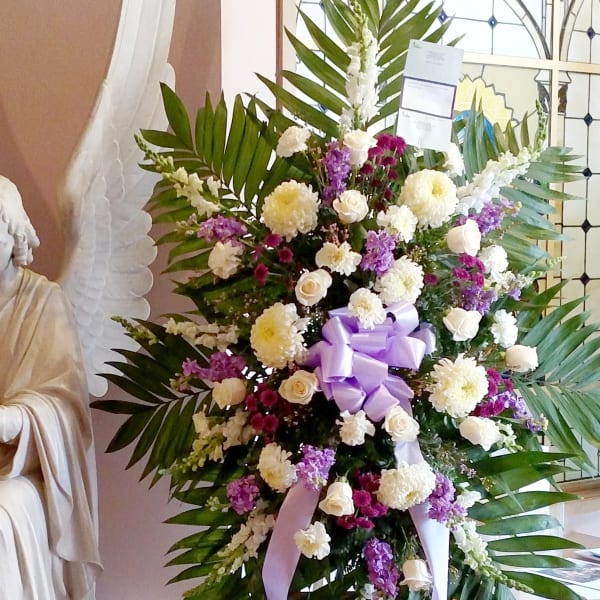 Large standing floral spray with white and purple flowers and a lavender ribbon