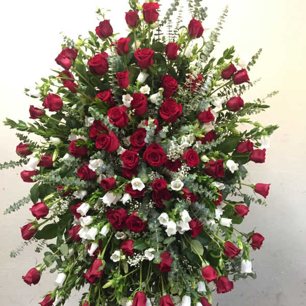 Large standing spray of red roses and white flowers on an easel
