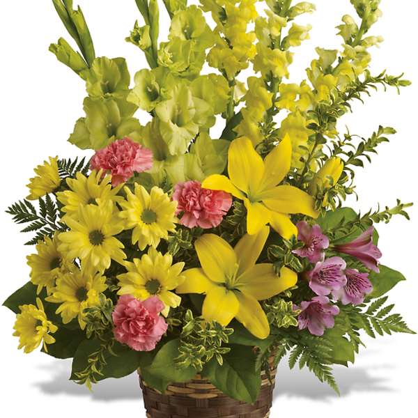 Yellow mixed flower arrangement in a woven basket with pink accents