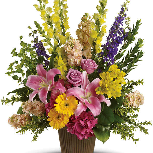 Mixed bouquet with pink lilies, roses, and yellow flowers in a brown vase