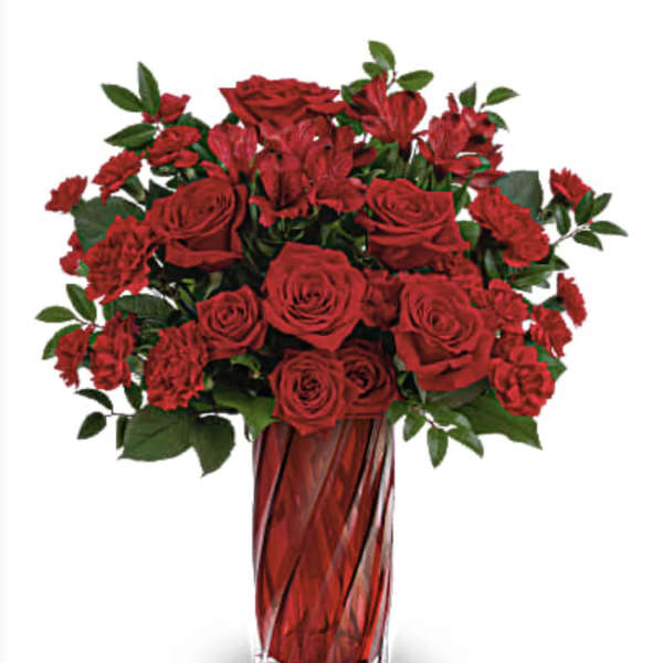 Red roses and carnations in a tall red glass vase