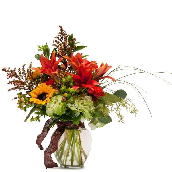 Bright mixed bouquet in a glass vase with sunflowers, lilies, and hydrangeas