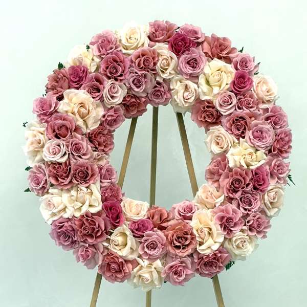 Heart-shaped wreath of pink and cream roses on a wooden easel
