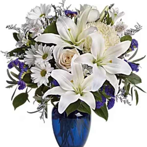 White lilies and daisies in a blue glass vase