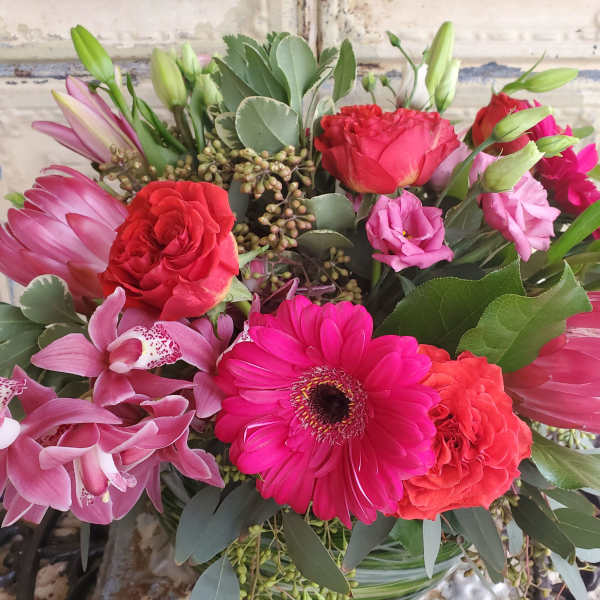 Mixed bouquet with pink orchids, red roses, and a bright pink gerbera daisy