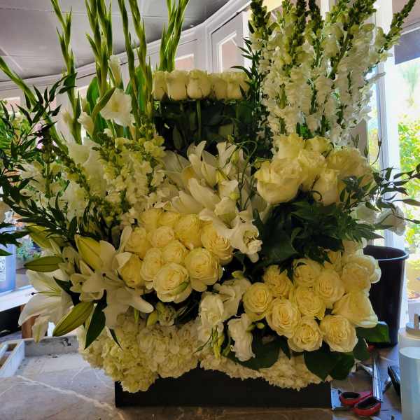 Large white floral arrangement with roses, lilies, and tall snapdragons