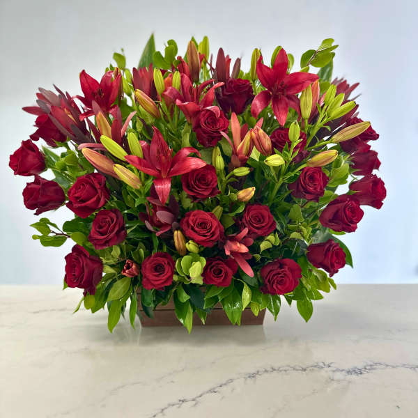 Red roses and lilies arranged in a low rectangular container
