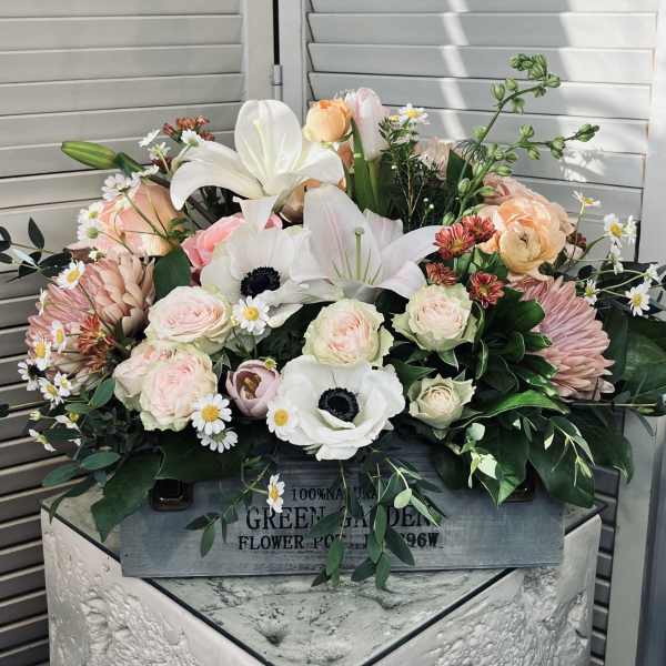 Mixed bouquet of pale pink and white flowers in a wooden box