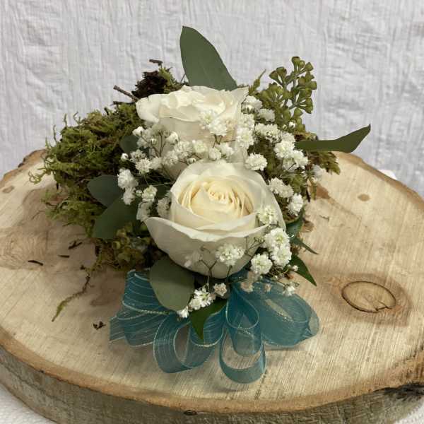 White roses with baby's breath and moss on a wood slice