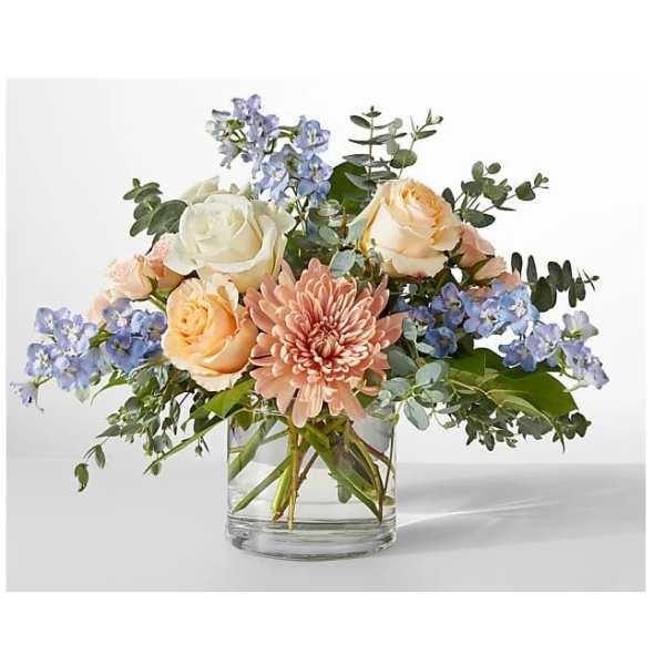 Mixed bouquet of roses, a pink chrysanthemum, and blue flowers in a glass vase