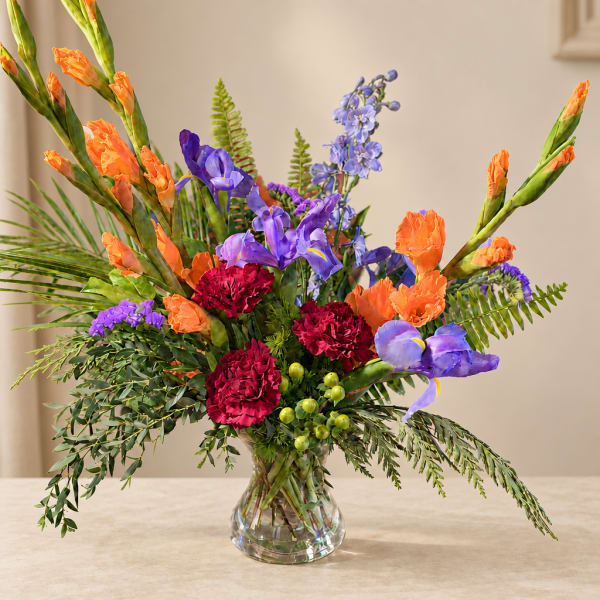 Colorful bouquet in a clear glass vase with orange, purple, and red flowers