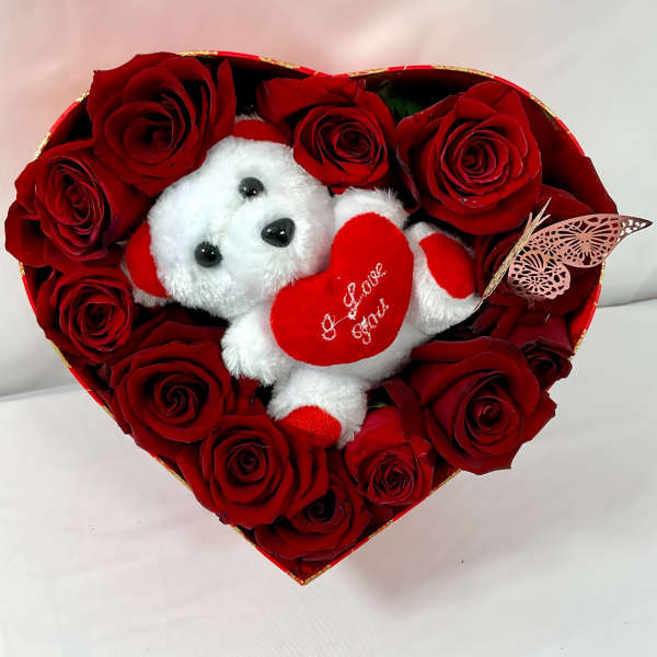 Heart-shaped box of red roses with a small teddy bear holding a heart