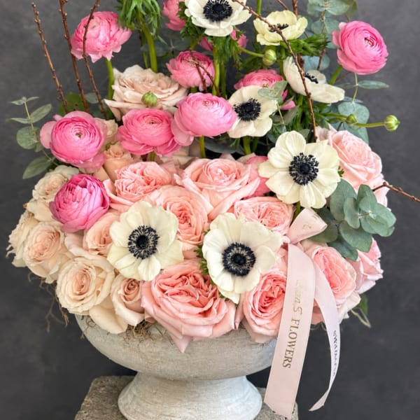 Pink and cream roses with white anemones in a pedestal vase