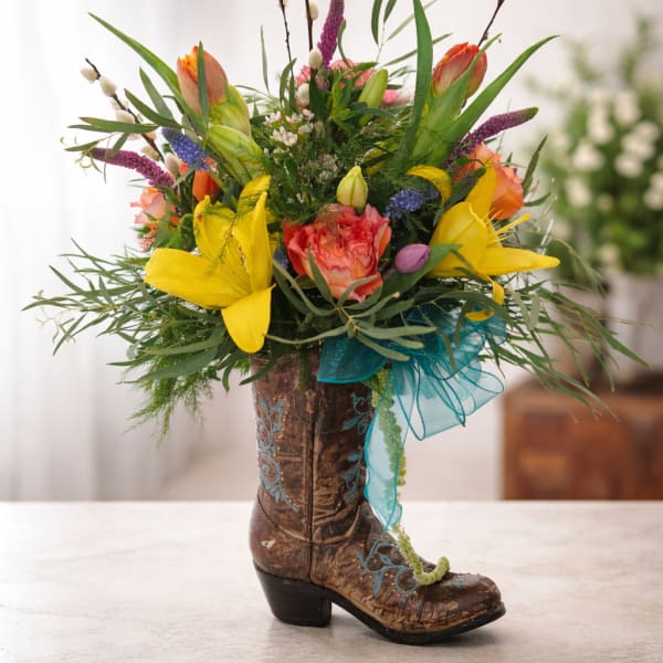 Colorful flower arrangement in a decorative cowboy boot vase