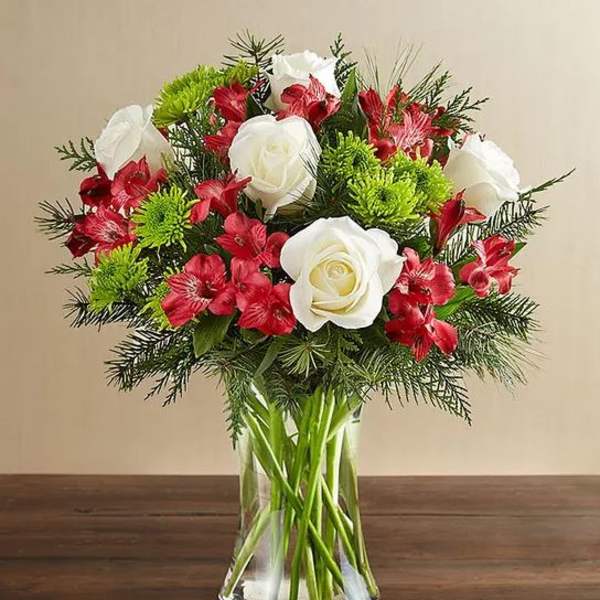 Bouquet of white roses and red flowers in a clear glass vase