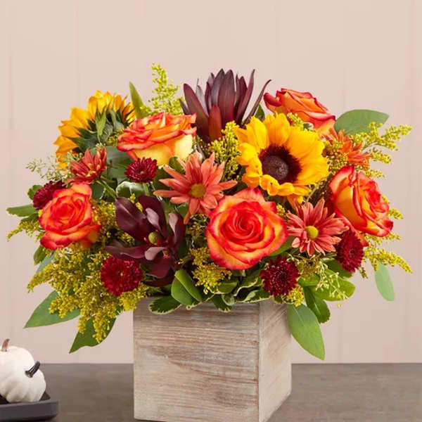 Mixed bouquet of orange roses and sunflowers in a wooden box