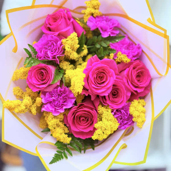 Bouquet of hot pink roses and carnations with yellow filler flowers