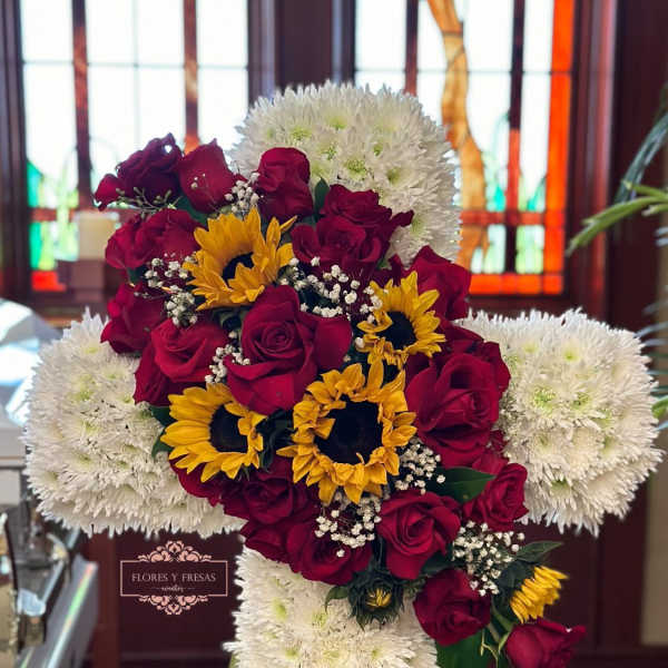 Cross-shaped floral arrangement with red roses, yellow sunflowers, and white chrysanthemums