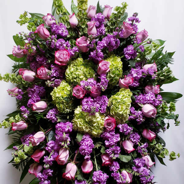 Large standing spray of pink roses, purple flowers, and green hydrangeas