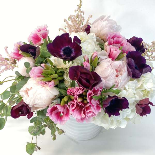 Pink and white bouquet with dark purple blooms in a white vase