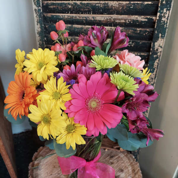 Colorful mixed bouquet in a glass vase with a pink ribbon