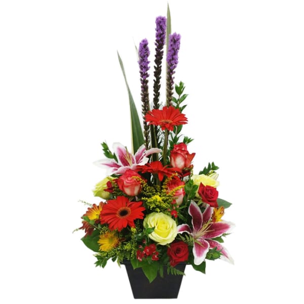 Tall mixed flower arrangement in a black vase with red, pink, yellow, and purple blooms