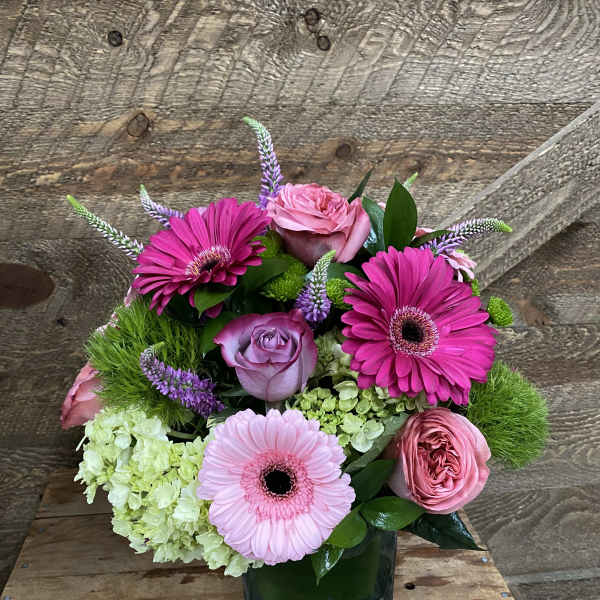 Pink and lavender flower arrangement in a square glass vase