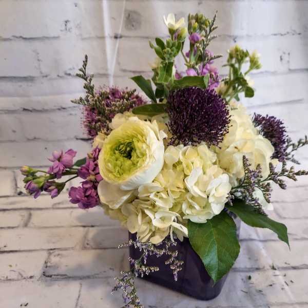 Bouquet of white and purple flowers in a dark vase