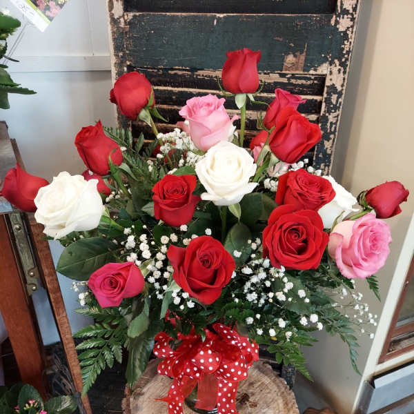 Bouquet of red, pink, and white roses with baby's breath in a glass vase