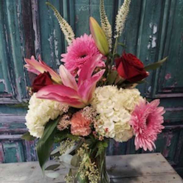 Pink lilies, roses, and hydrangeas in a glass vase