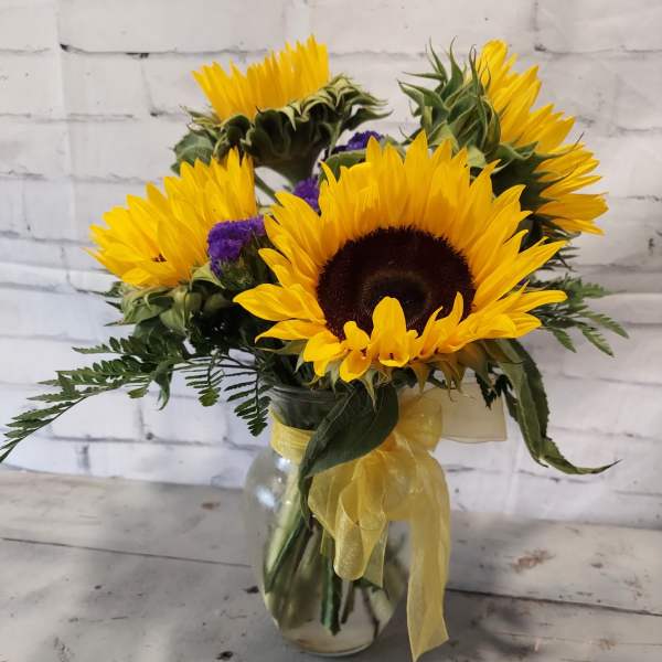 Sunflower bouquet in a glass vase with yellow ribbon