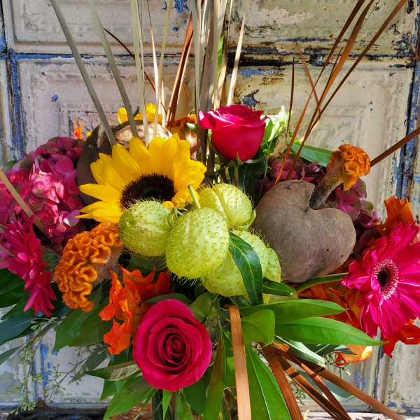Mixed bouquet with roses, sunflowers, and bright tropical blooms in a glass vase