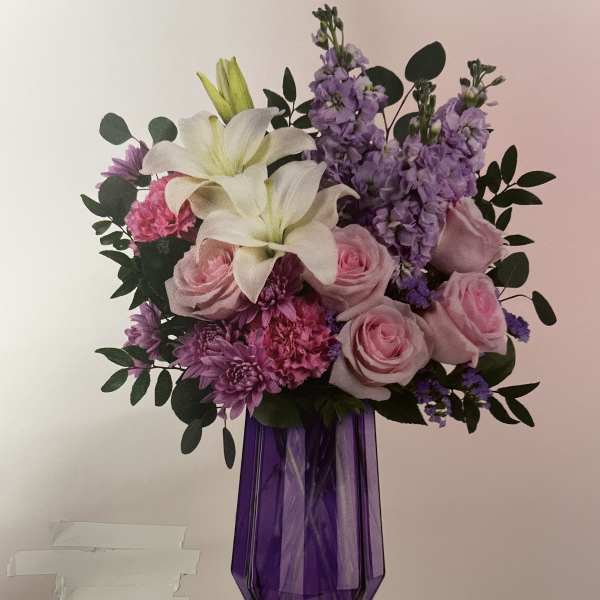 Pink and purple bouquet with white lilies in a purple vase