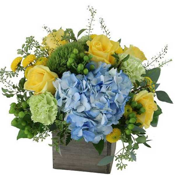 Blue hydrangeas and yellow roses in a wooden box arrangement
