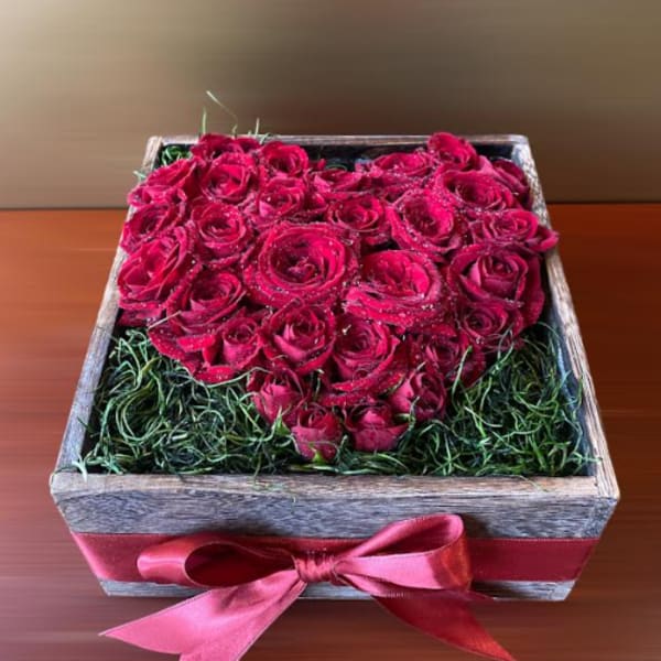 Heart-shaped box of red roses with a pink ribbon